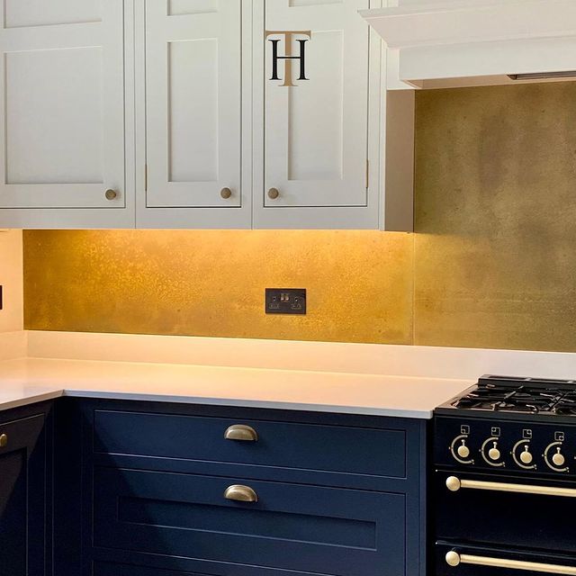 gold brass splashback in white and blue kitchen